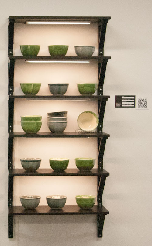 [My setup for the 18 replica thesis bowls I showed at GradEx, on five shelves with bowls on the middle shelf in a merchandise-display-like arrangement]